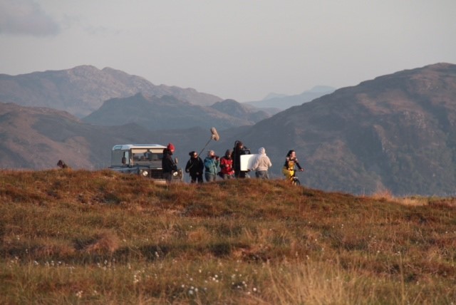 Film crew filming in rural hillside area 