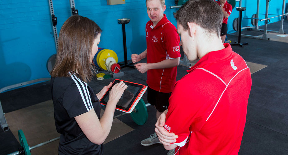 Three sports students analysing data on a tablet device