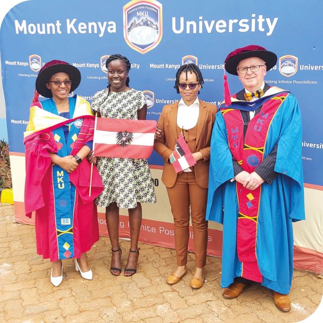 Four people with two in gowns celebrating the Mount Kenya uni partnership