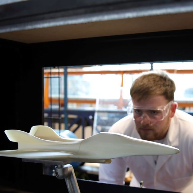Image of UWS student looking at fighter jet solid model in wind tunnel.