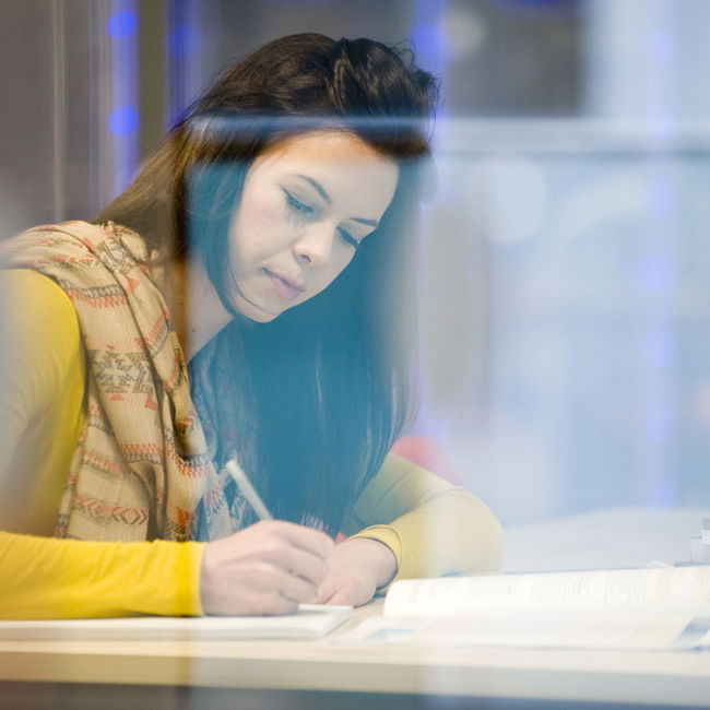 Female writing at a library desk