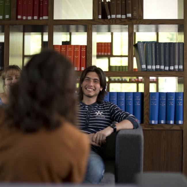 Students in seated area with bookcase