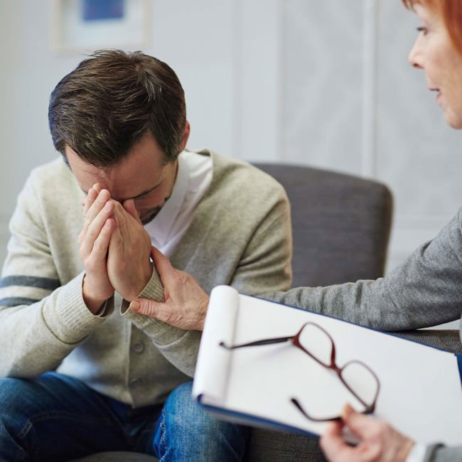 Cognitive Behavioural Therapy. Therapist holding paperwork and male patient