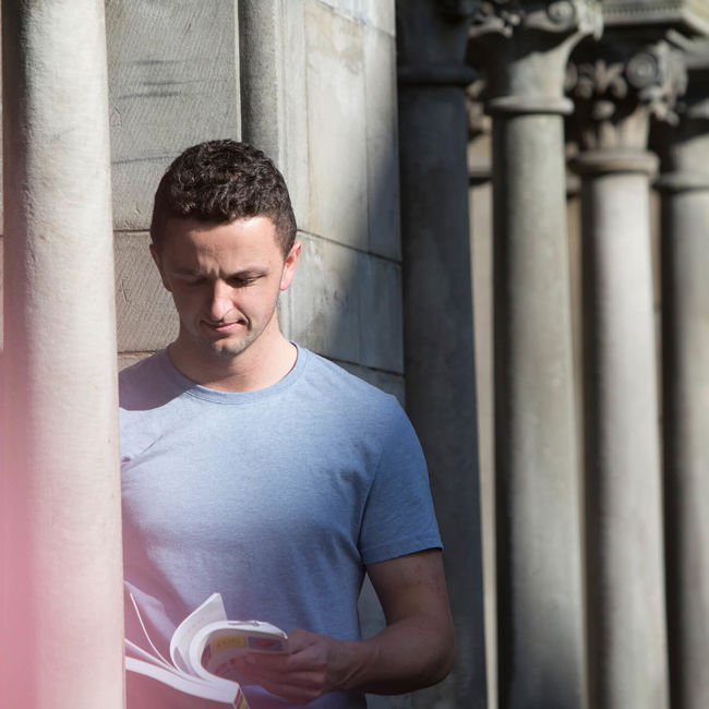 Male standing with a textbook