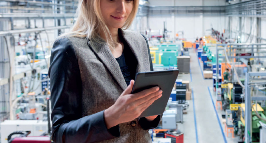 Student holding tablet in a factory setting
