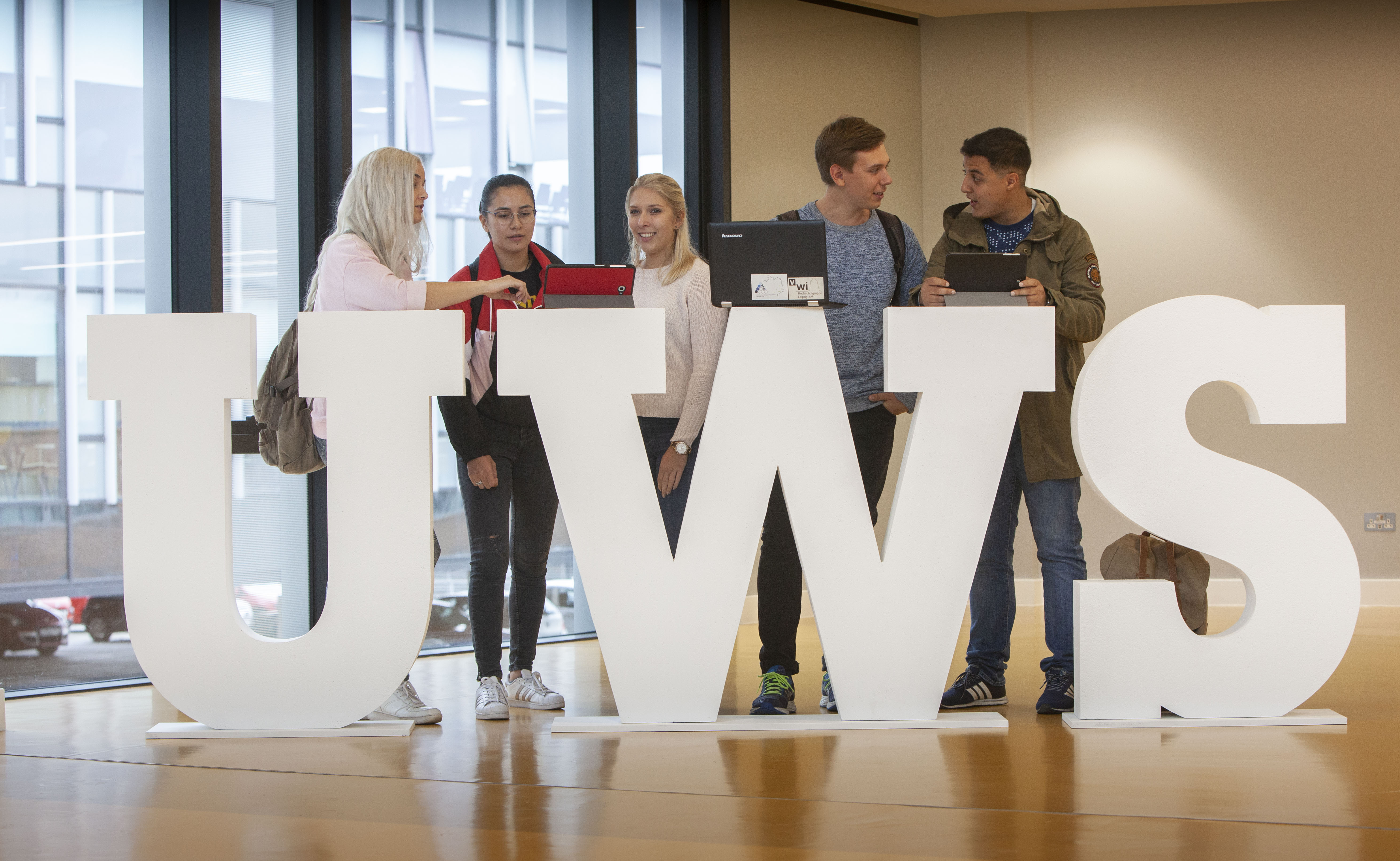 Students leaning on the UWS letters Lanarkshire campus