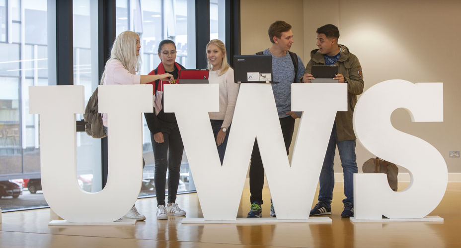 Students leaning on the UWS letters Lanarkshire campus