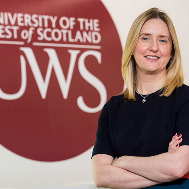Jo Maguire in front of UWS logo