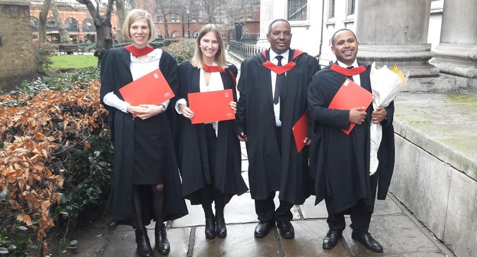 UWS students at graduation in gowns holding certificates