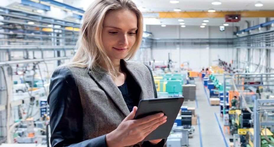 Student holding tablet in a factory setting