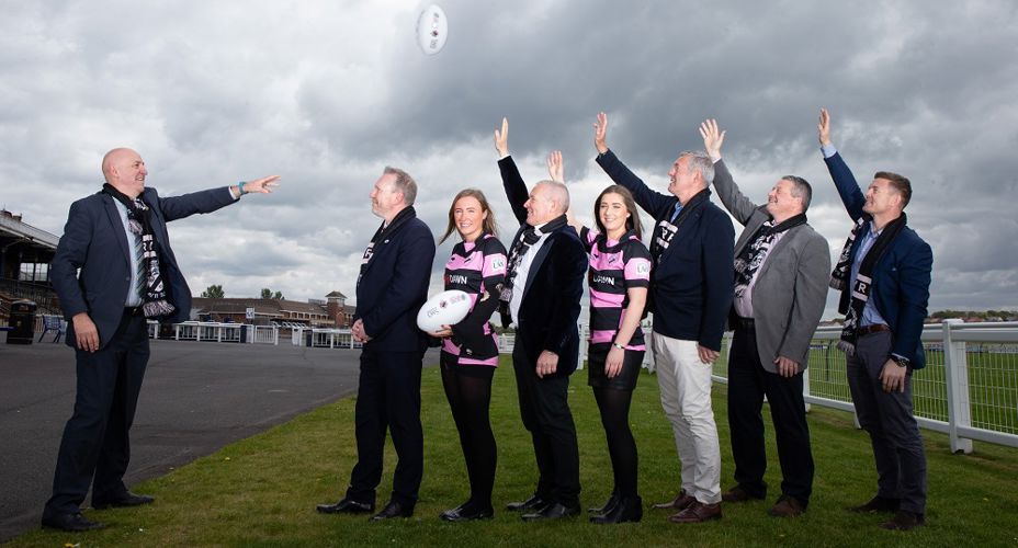 Prof Mahoney throwing rugby ball over Ayr Rubgy staff