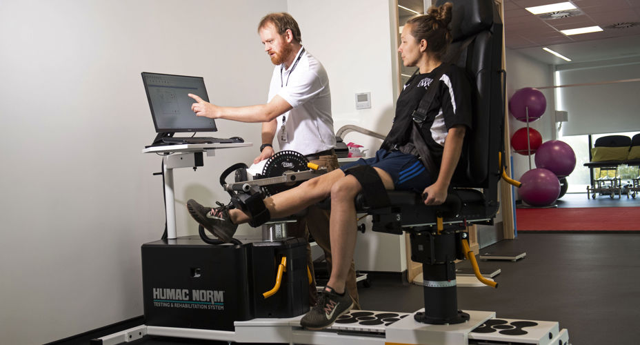 Lecturer supervising a student on fitness equipment