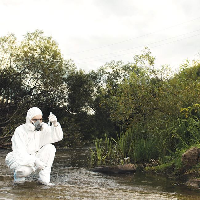 Applied Biomedical Science and Zoology |Person wearing safety suit in river taking a water sample