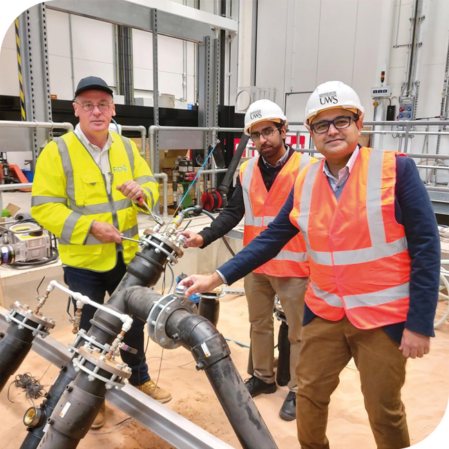 Three men in hi-vis with construction hats on site.